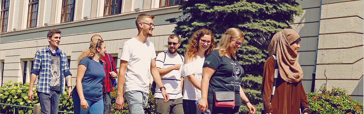 Zdjęcie przedstawia grupę studentów idącą obok budynku Uniwersytetu Przyrodniczego./A group of students walking beside the main building of the university.
